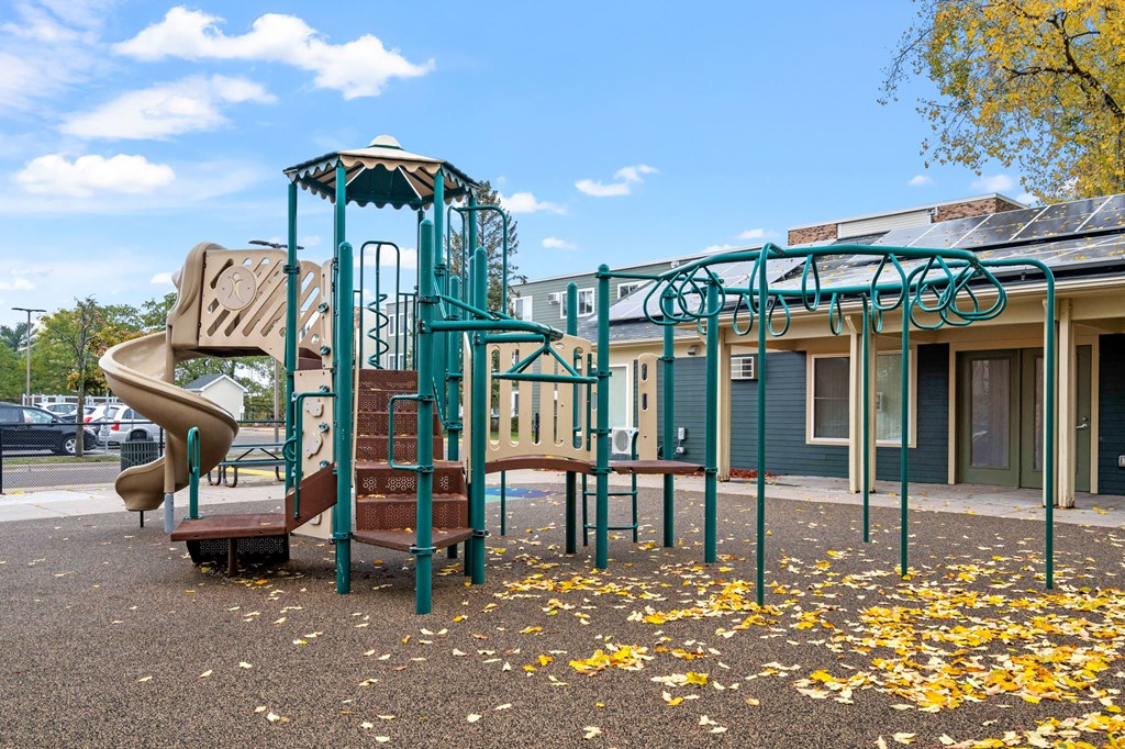 a playground with a slide and climbing equipment in front of a building