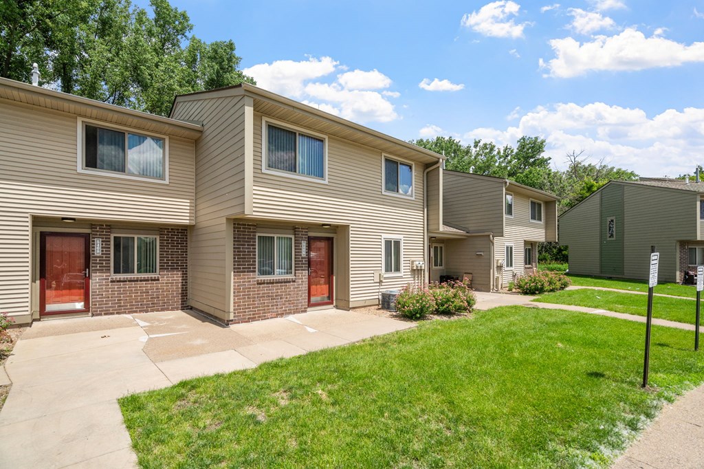 exterior view of two story apartment buildings with a sidewalk and grass