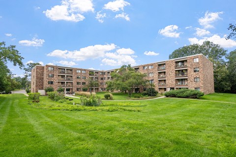 a large brick apartment building with green grass and trees