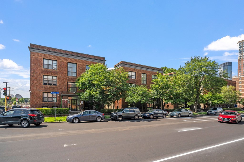 a city street with cars parked in front of a brick building