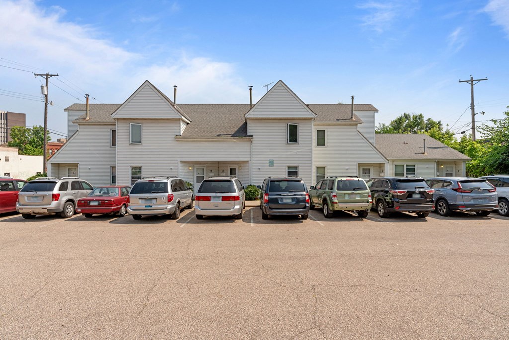 a parking lot full of cars in front of a white house