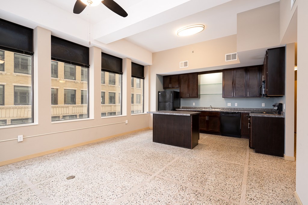 an empty room with a kitchen and a large window