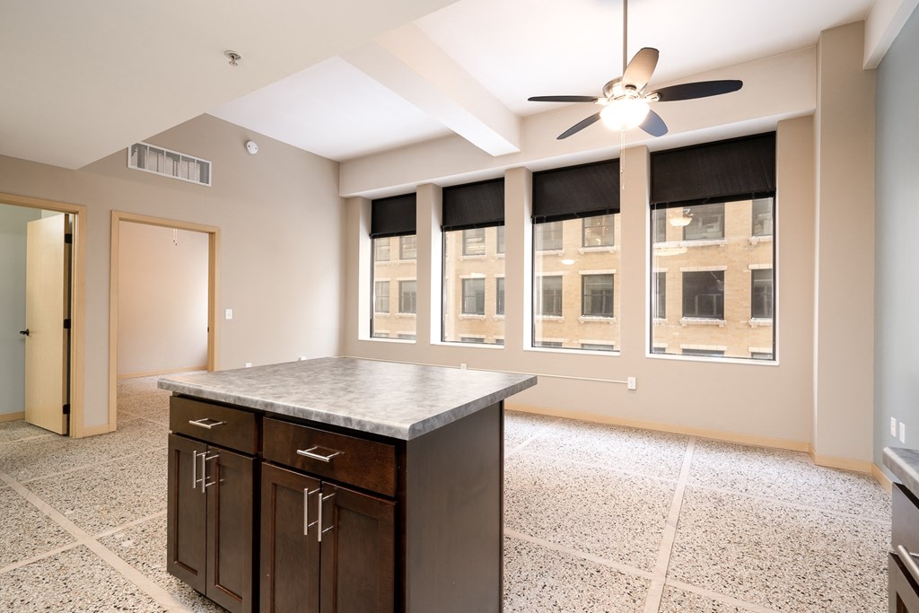 an empty kitchen with a large window and a ceiling fan