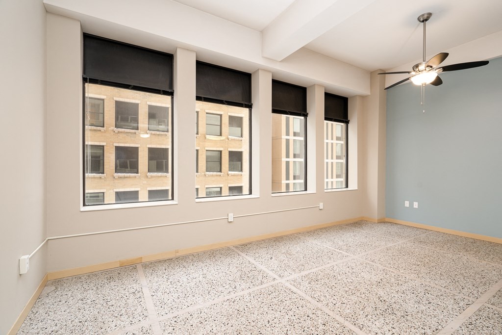 an empty room with windows and a ceiling fan
