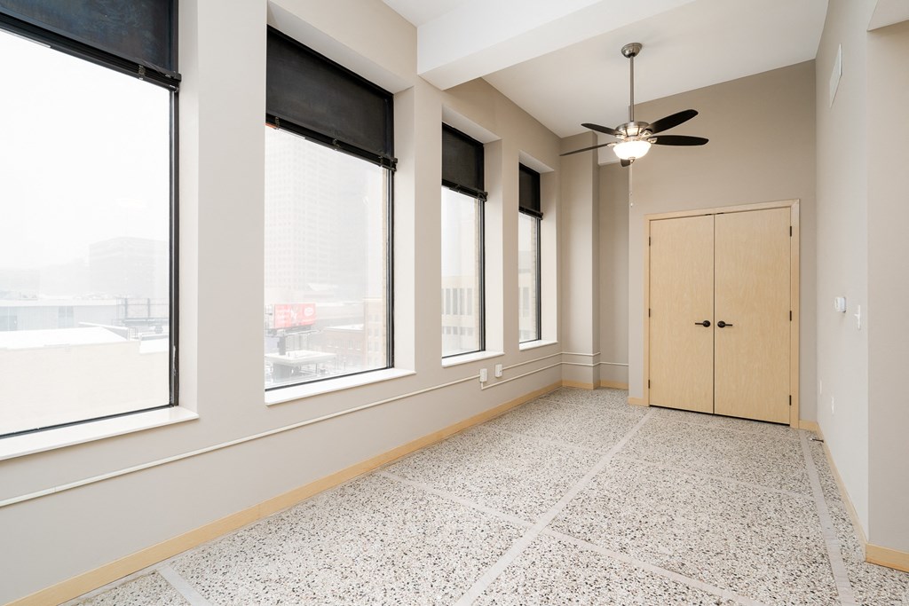 an empty room with three windows and a ceiling fan