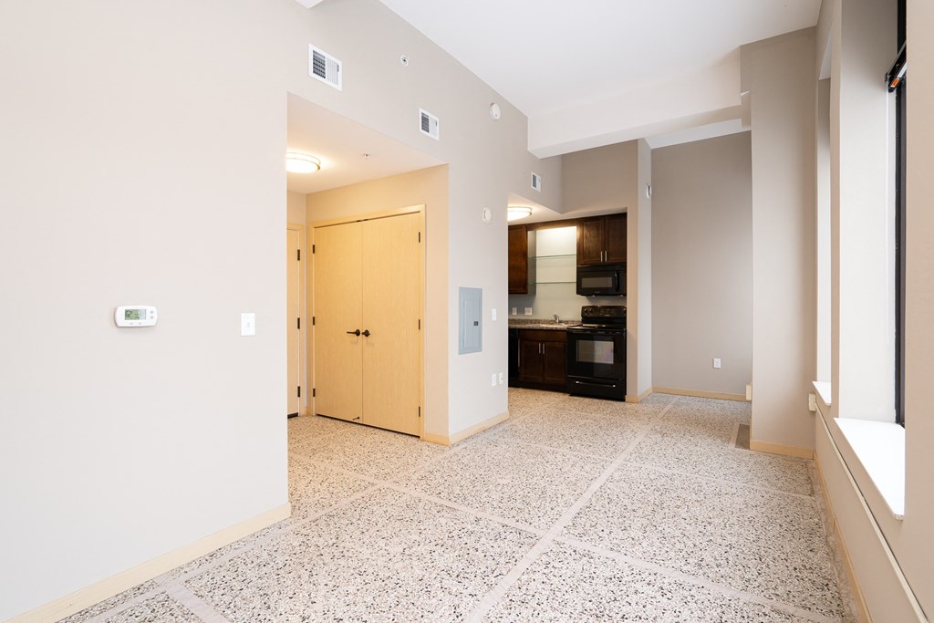 an empty living room and kitchen with a door to the hallway