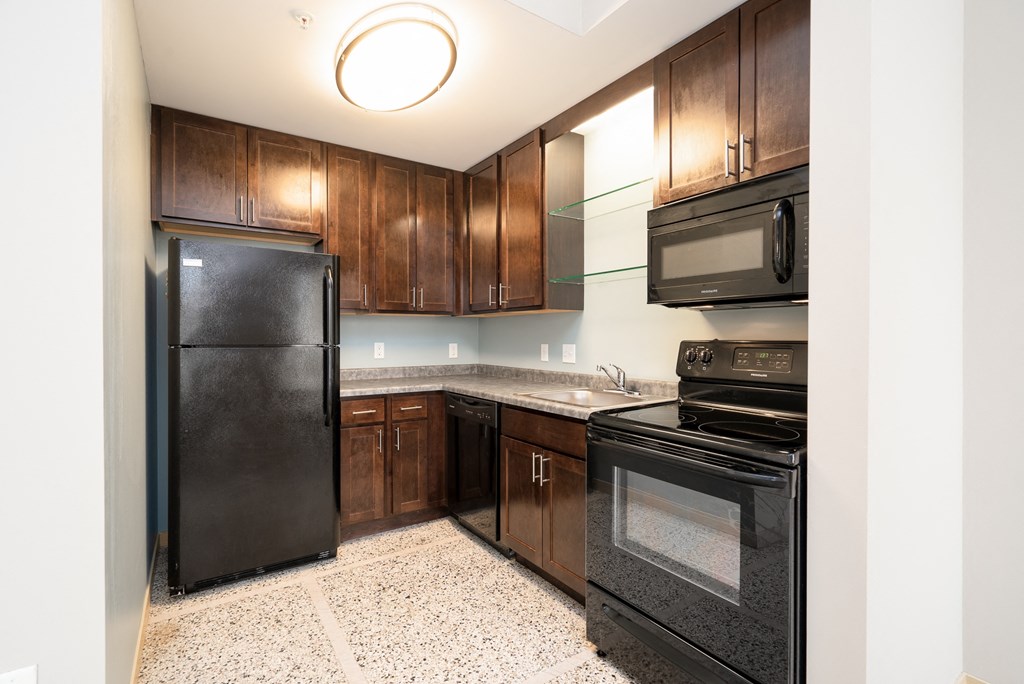 a kitchen with black appliances and dark wood cabinets