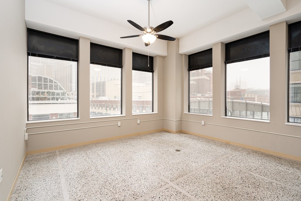 an empty room with windows and a ceiling fan