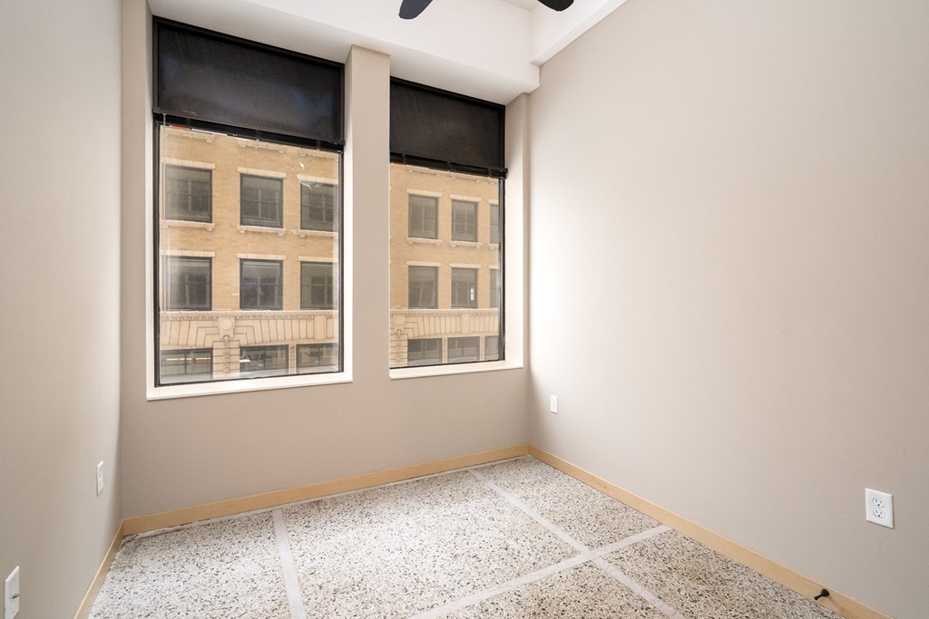 an empty room with two windows and a tiled floor