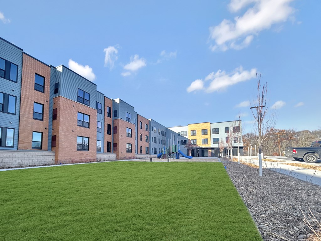 a green lawn in front of a row of apartment buildings