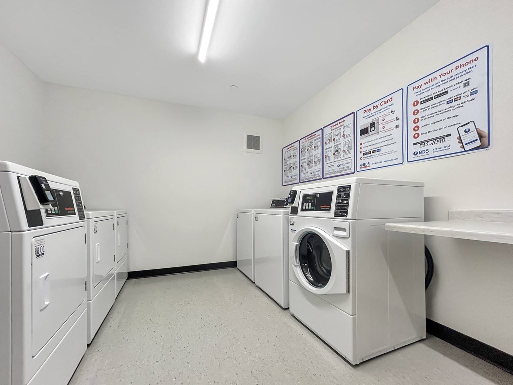 a laundry room with washes and dryers and a sign on the wall