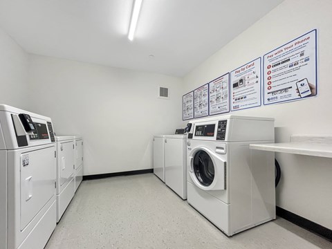 A laundry room with a sign on the wall and several washing machines.