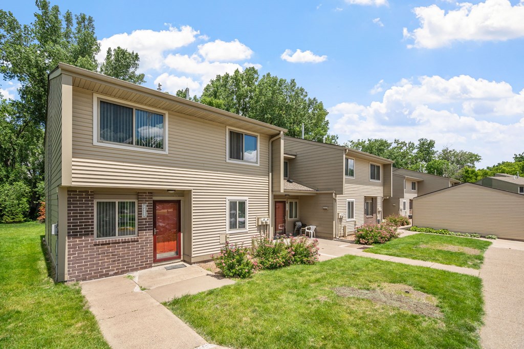 exterior view of two apartment buildings with a sidewalk and grass