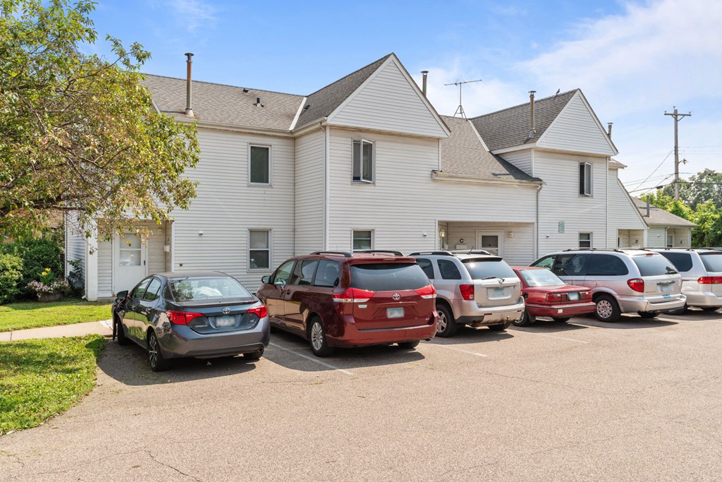 a parking lot full of cars in front of a white house