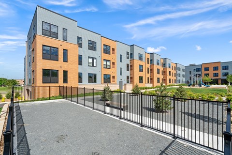 A row of modern apartment buildings with a black fence in front.