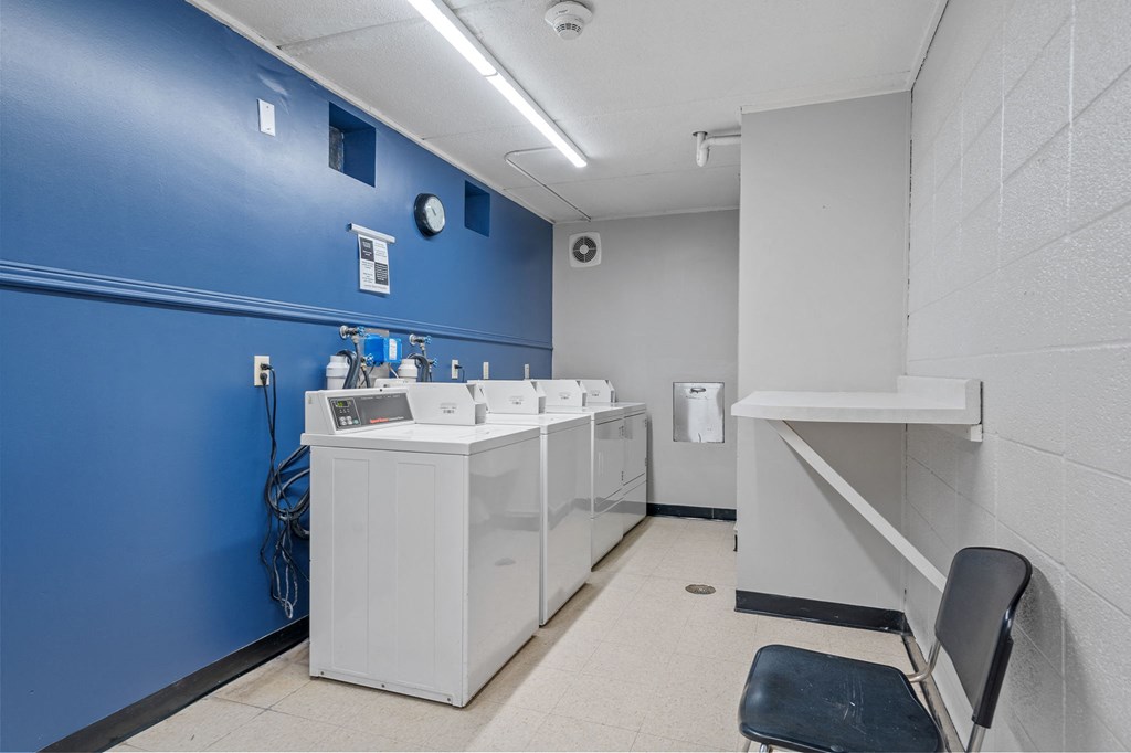 a public restroom with a blue wall and white washing machines