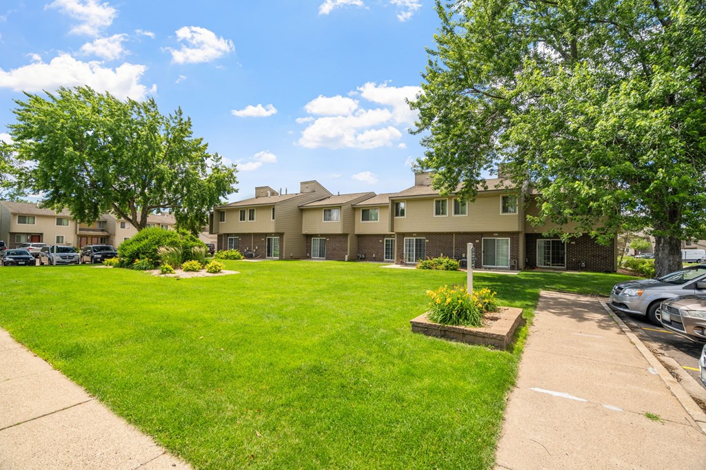 the view of an apartment building with a lawn and trees