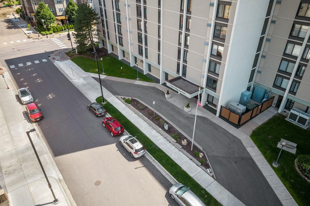 an aerial view of a street with cars parked in front of an apartment building