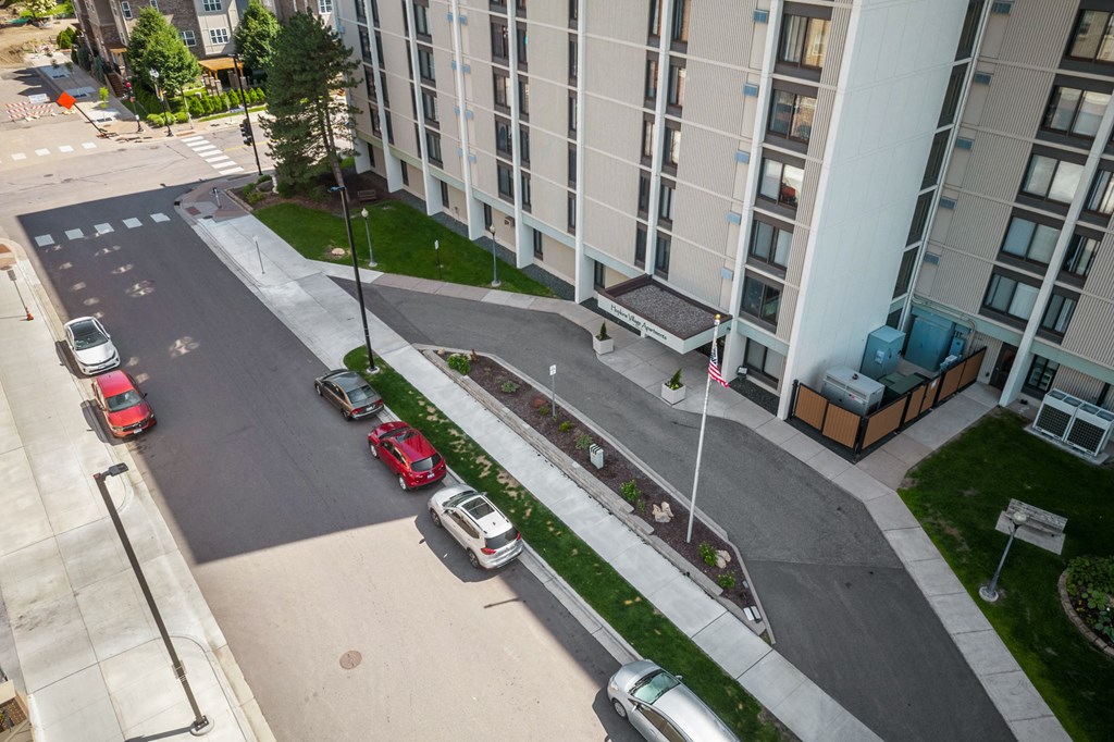 an aerial view of a street with cars parked in front of an apartment building