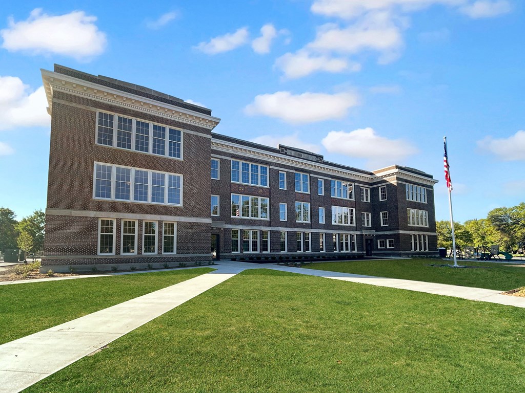 a brick building with a lawn and an flag