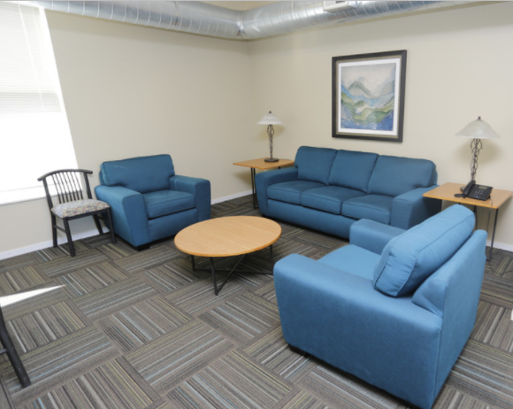 A living room with blue furniture and a painting on the wall.