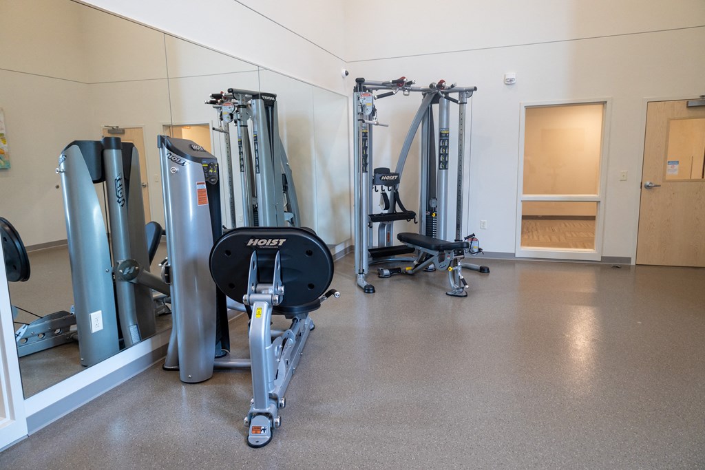 a gym with cardio equipment and weights on the floor