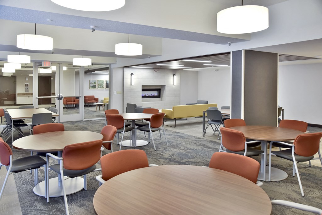 a cafeteria area with tables and chairs and a tv