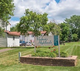 A sign for Vashon's Highlands is in the foreground of a grassy area.
