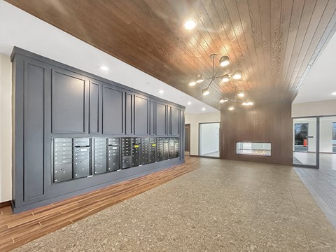 A modern lobby with dark grey mailboxes and a wooden ceiling.