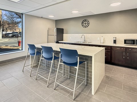 A kitchen with a bar area and blue chairs.