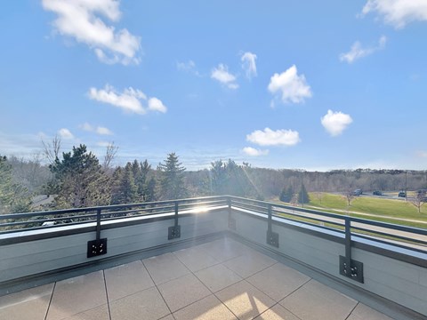 the view from the balcony of a building overlooking a field and trees