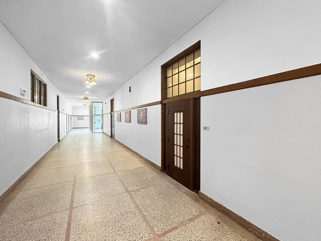 a long hallway with white walls and a door in the middle