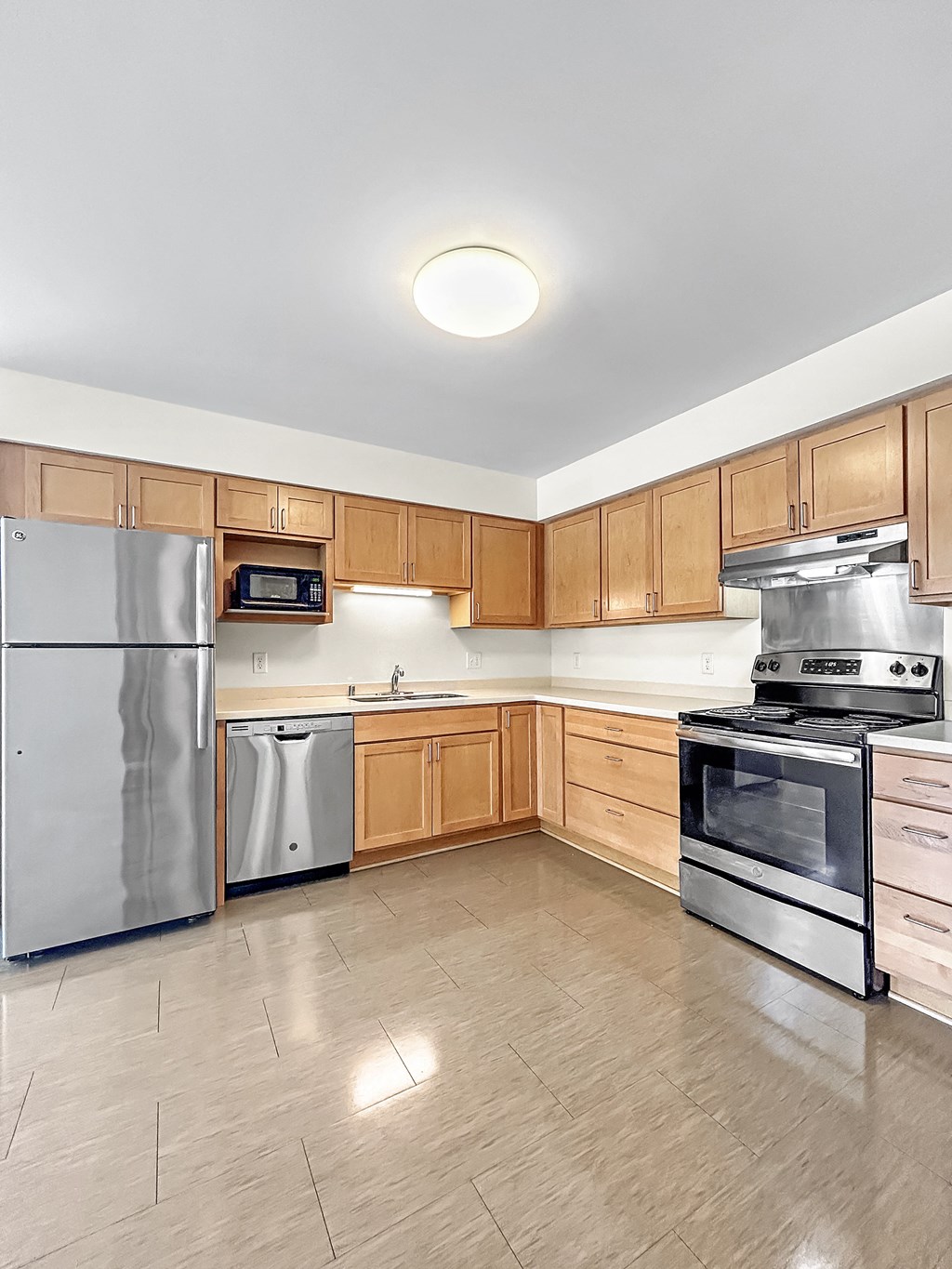 a large kitchen with stainless steel appliances and wooden cabinets