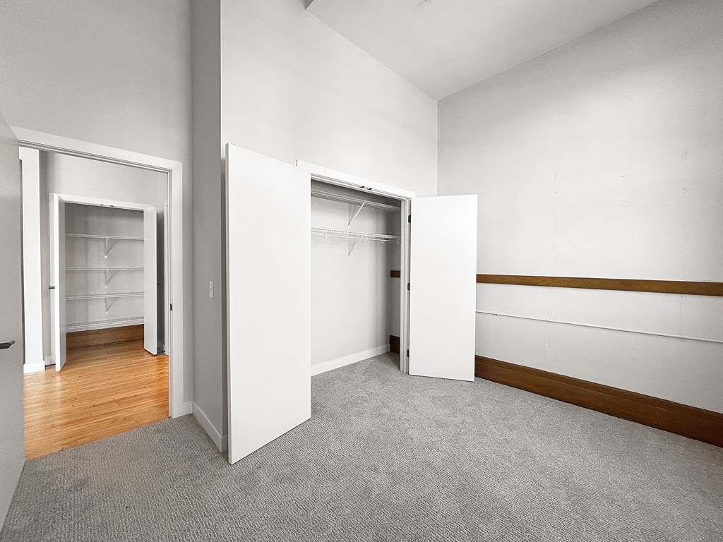 an empty room with white walls and doors to closets