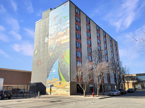 A large mural on the side of a building depicts a scene with birds and a body of water.
