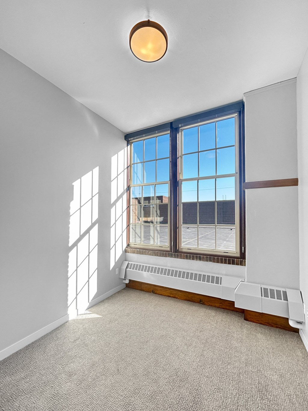 an empty room with large windows and a carpeted floor