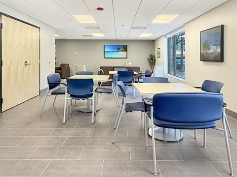 A conference room with blue chairs and a television on the wall.