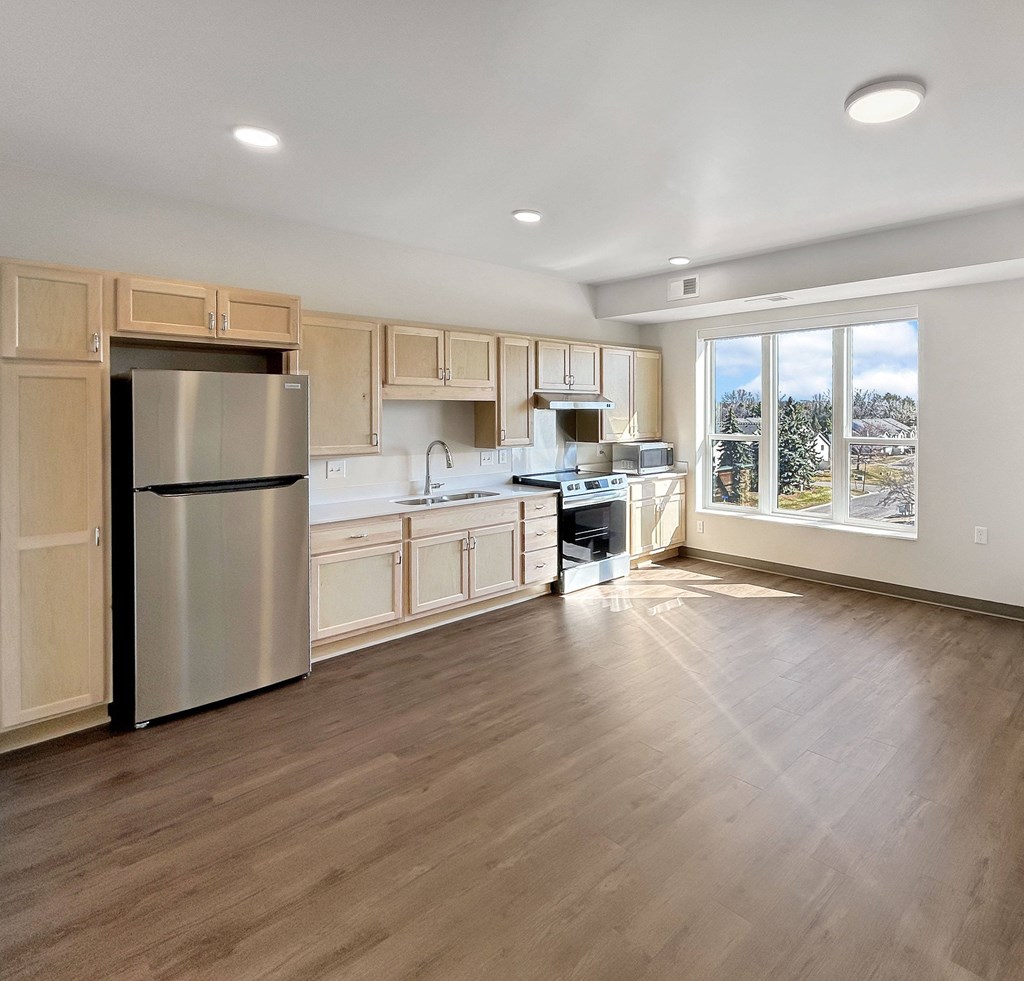 A kitchen with wooden cabinets and a stainless steel refrigerator.