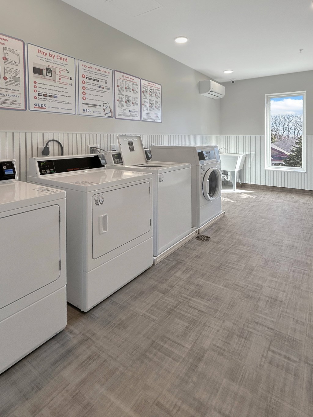 A laundromat with washers and dryers and instructions on the wall.