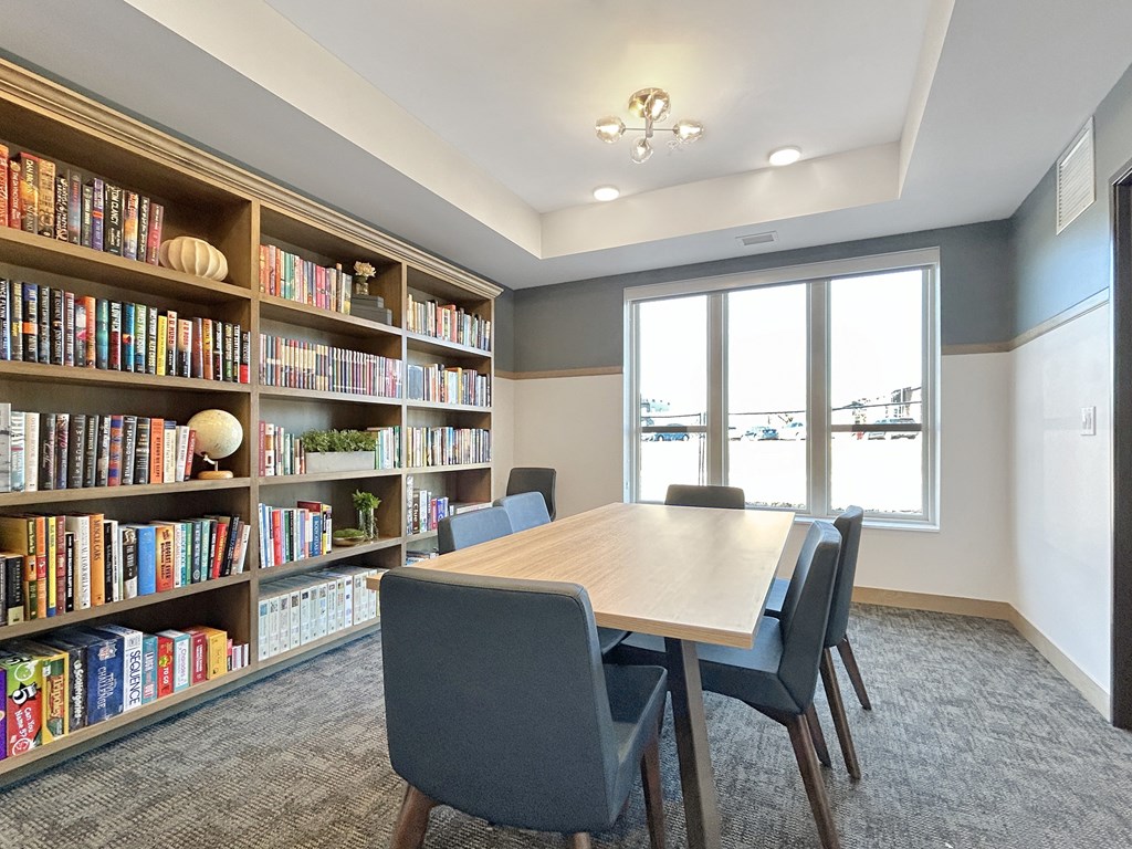 A room with a table, chairs and a bookshelf.