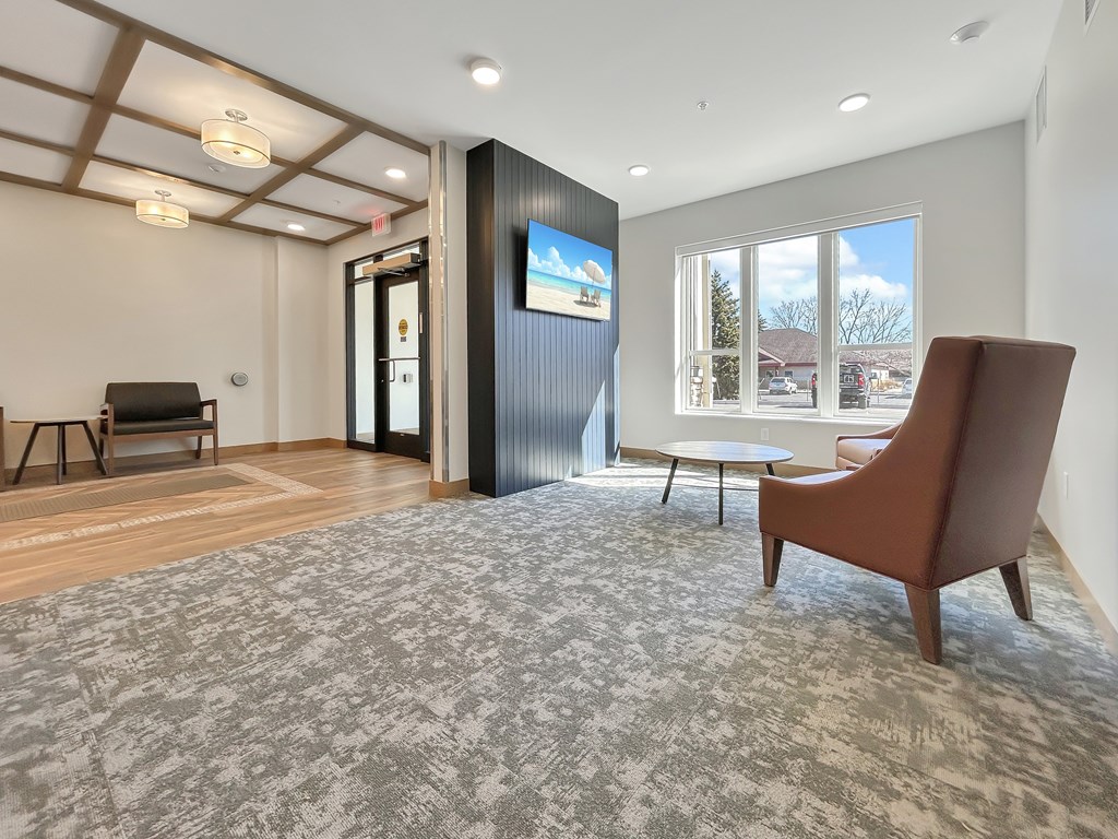 A room with a grey carpet and a brown chair.