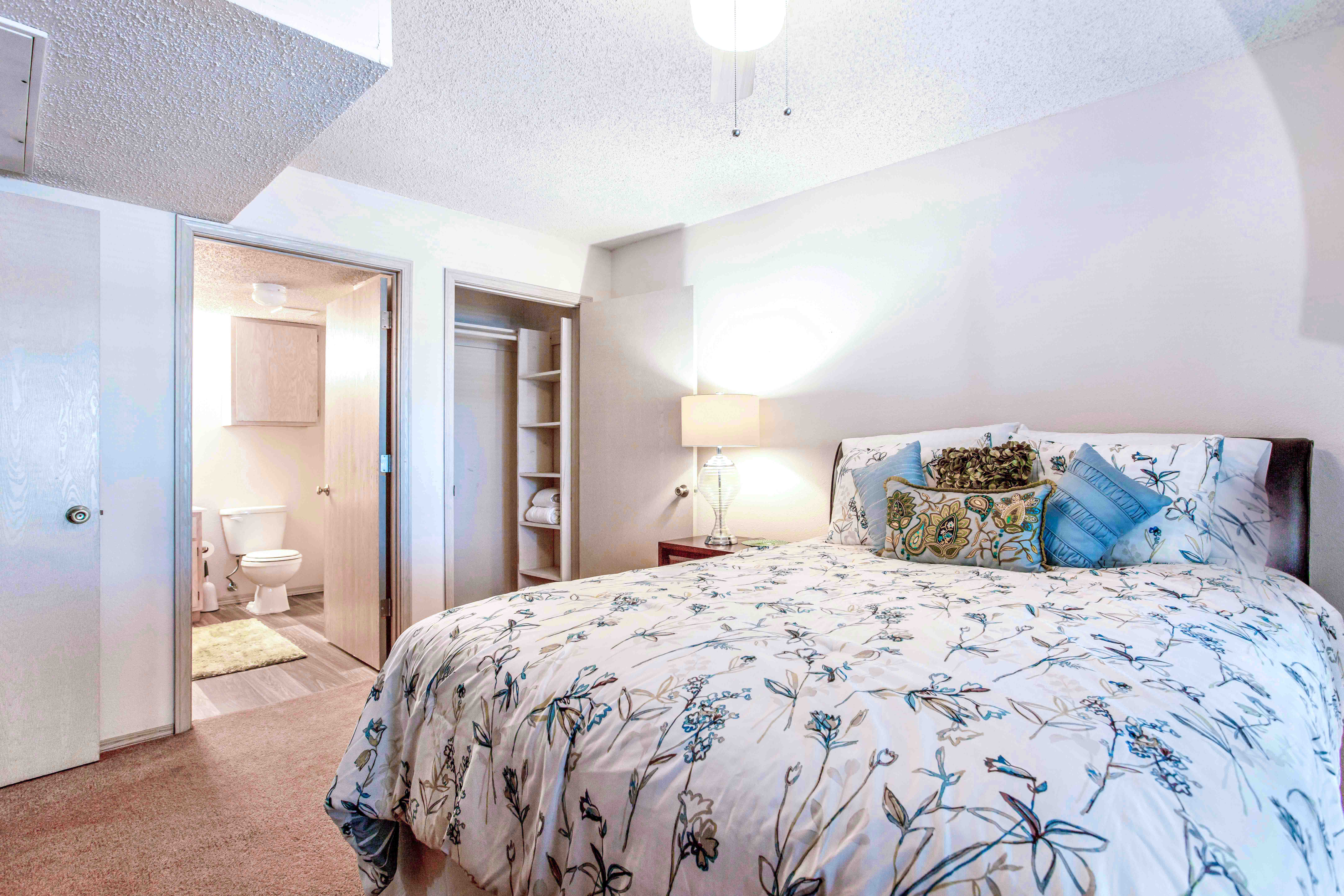 a bedroom with a bed and a bathroom in the background