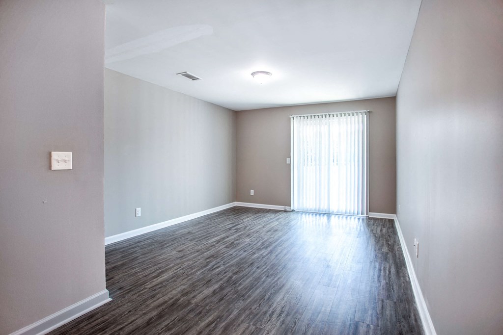 an empty living room with wood flooring and a window
