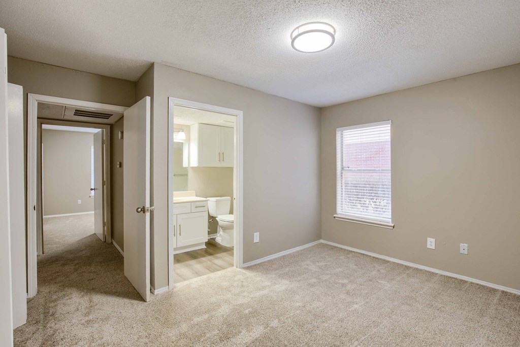 a bedroom with a bathroom in the background