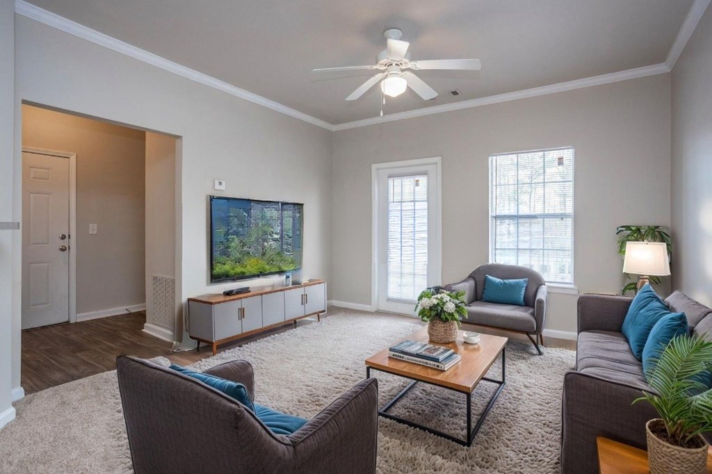 A living room with a brown chair, a grey couch, a coffee table, and a television.