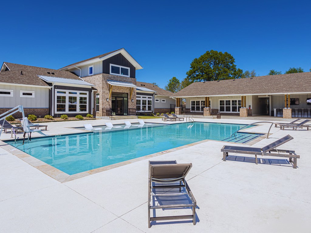 a swimming pool with lounge chairs and a house in the background