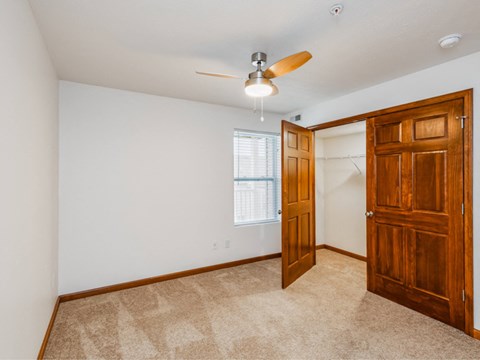 an empty bedroom with a closet and a ceiling fan