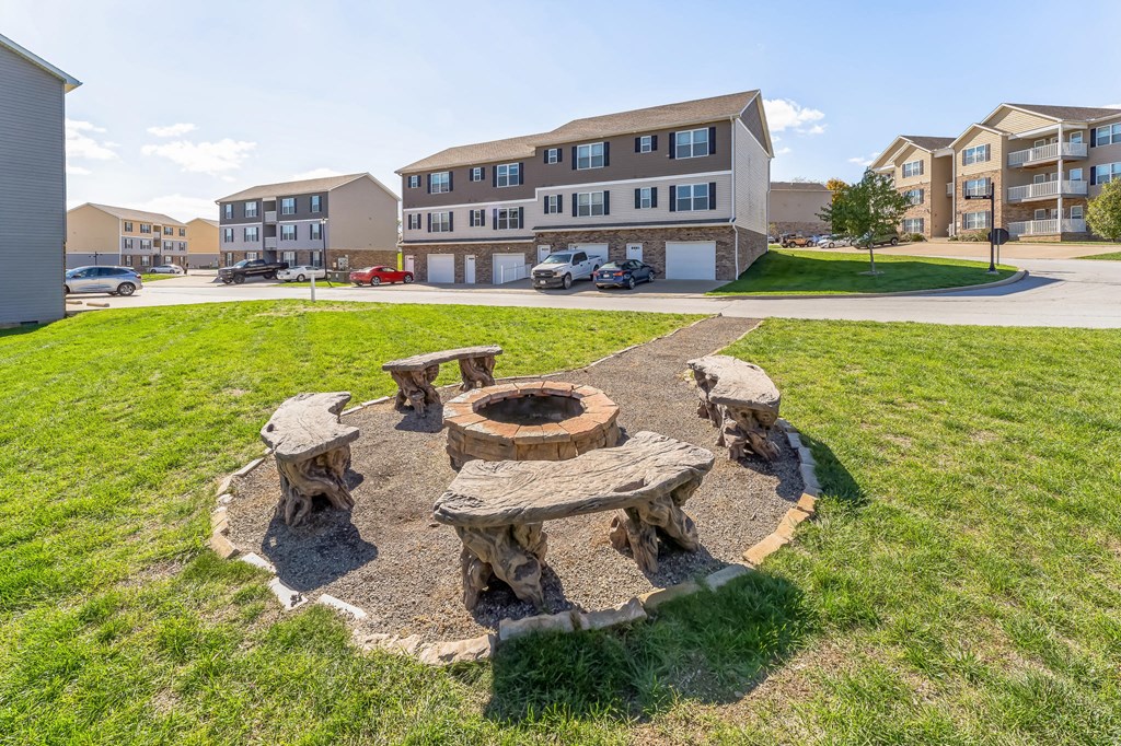 a fire pit with wooden benches in front of an apartment building