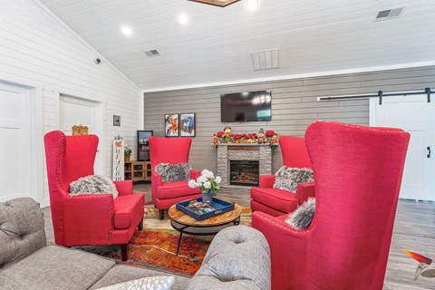 a living room with red chairs and a fire place