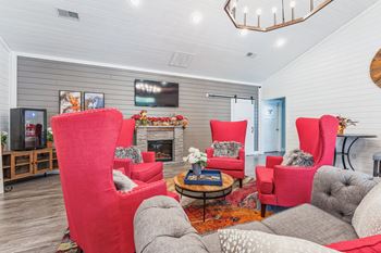 a living room with red chairs and a fireplace
